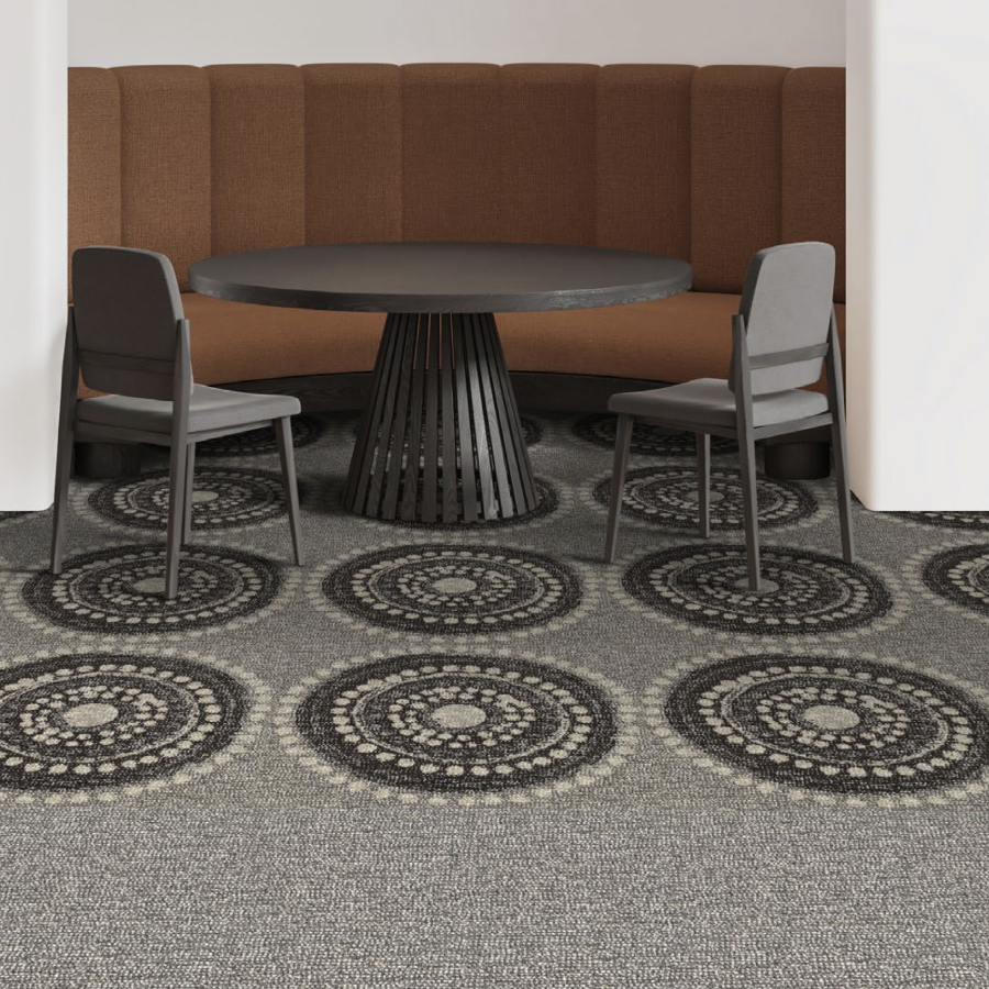 Modern room with a round black table, two gray chairs, and a curved brown bench. The carpet features intricate circular patterns in grayscale.