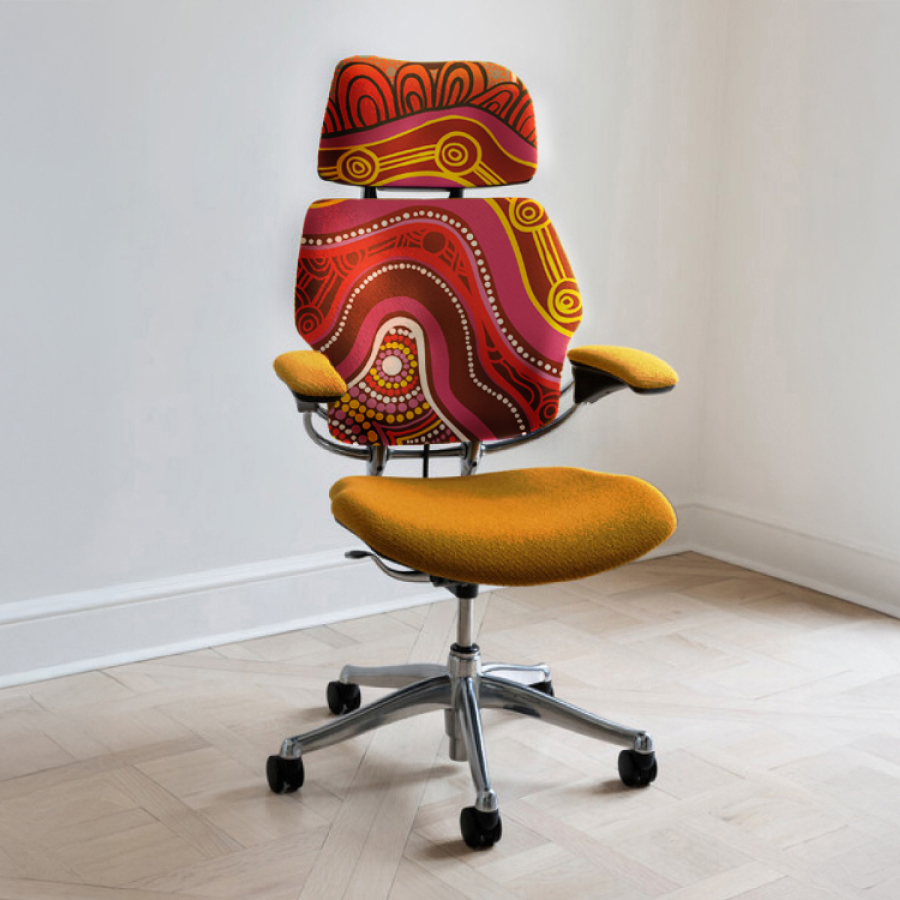 An office chair with a vibrant backrest featuring red and yellow Aboriginal art patterns.