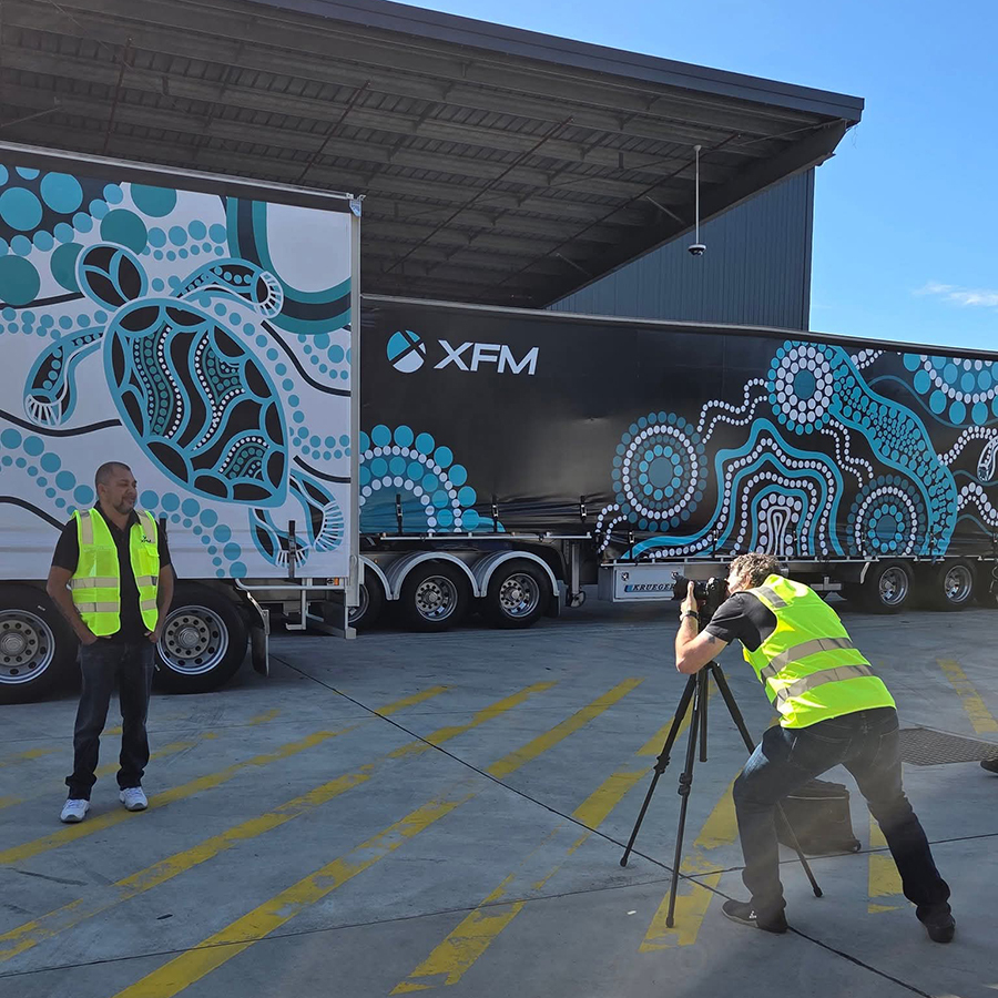 A photographer taking photos of Kevin Bynder in a yellow vest standing beside a truck with vibrant turtle and dot patterns