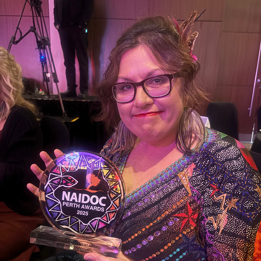 Brooke- Louise O'Donnell smiles, holding a colourful NAIDOC Perth Awards 2025 trophy