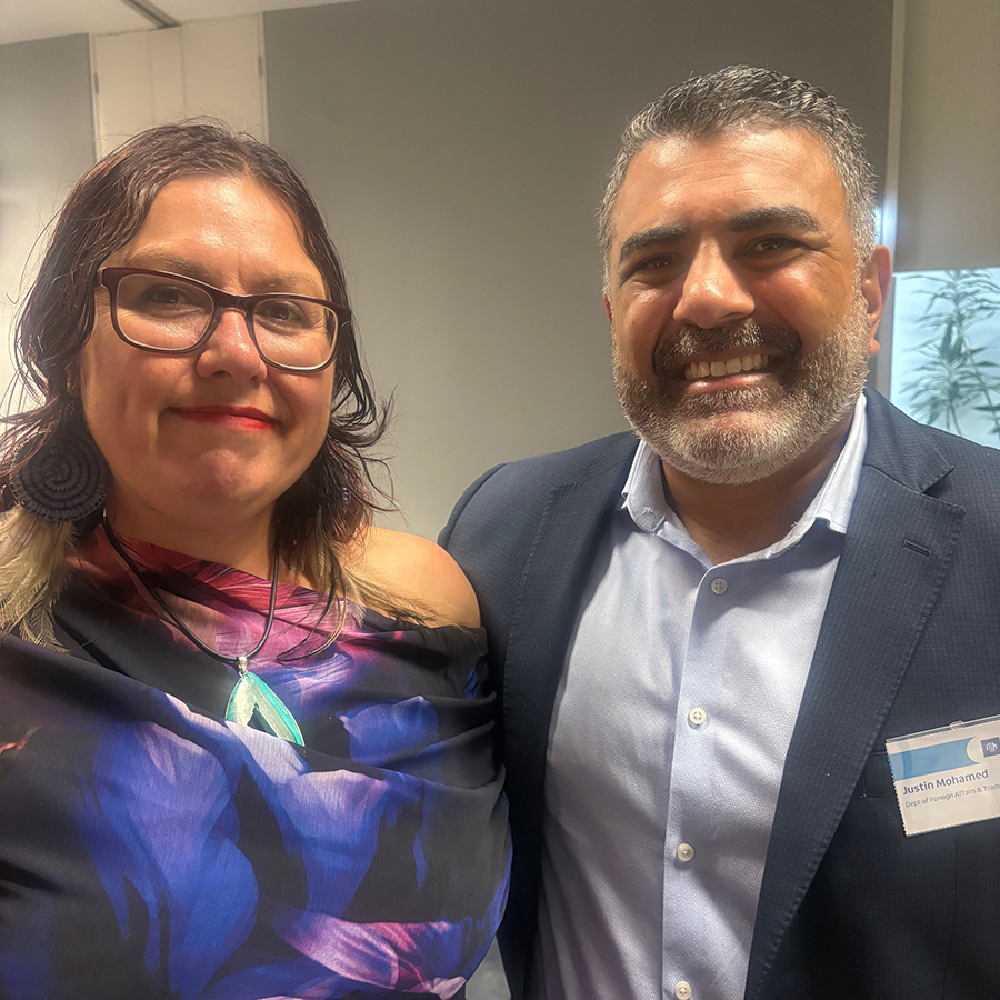 A woman and a man smile warmly in a professional event