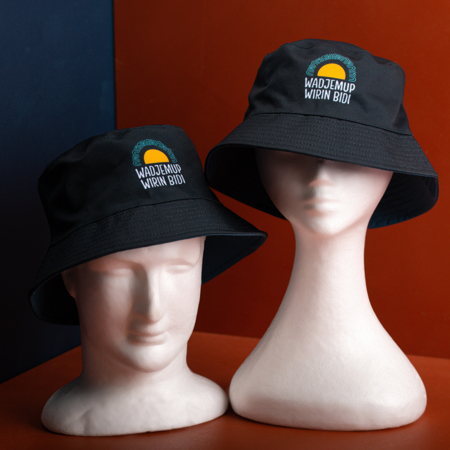 Two white mannequin heads wearing black bucket hats with a colorful logo and the text 