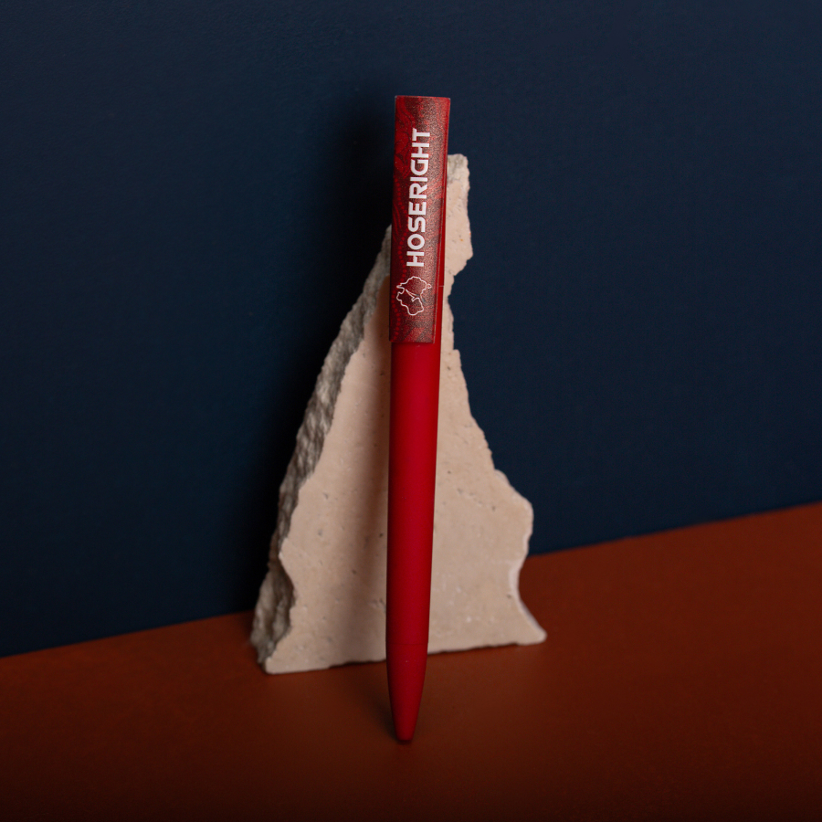 A red pen with a logo leans against a jagged beige rock against a navy and brown background.