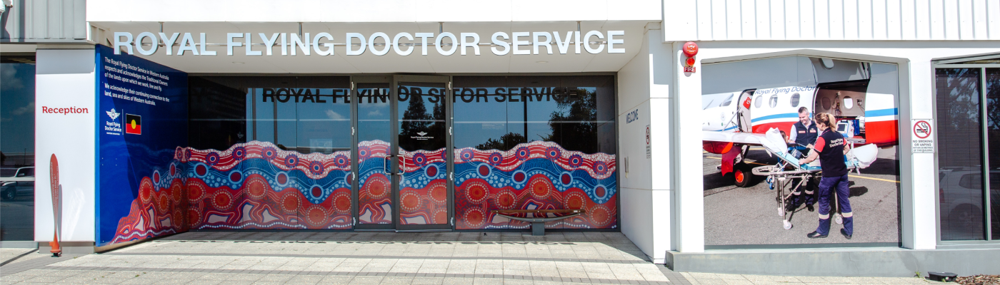 Front of the Royal Flying Doctor Service building featuring vibrant Indigenous art on glass doors