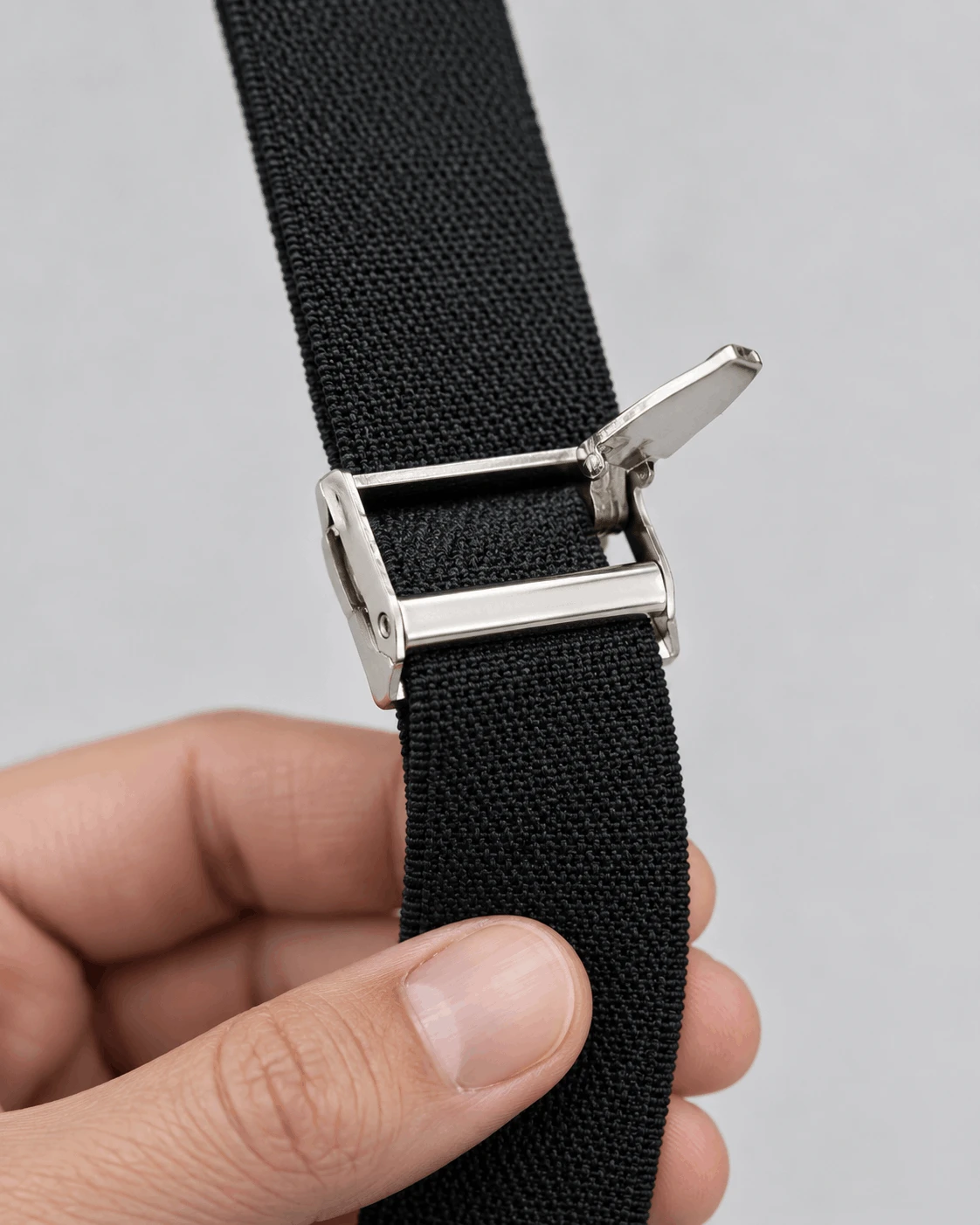 Close-up of a nickel flip and lock suspender adjuster on an elastic strap