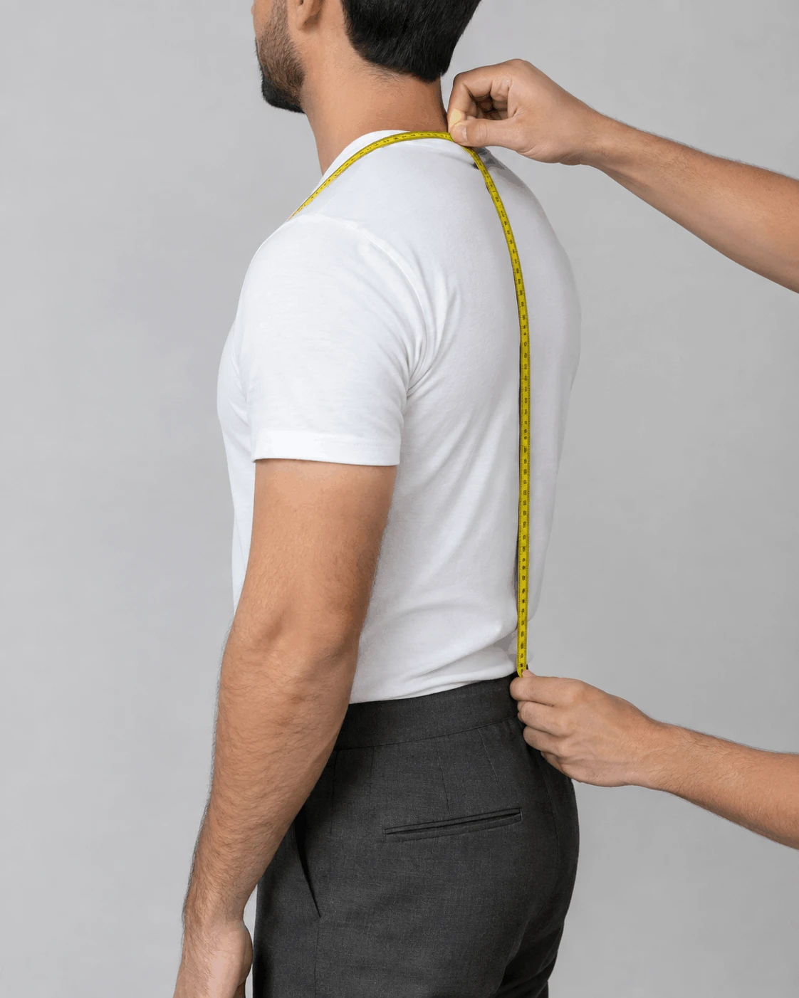 Measuring a man for suspenders with a tape measure over the shoulder and down the back