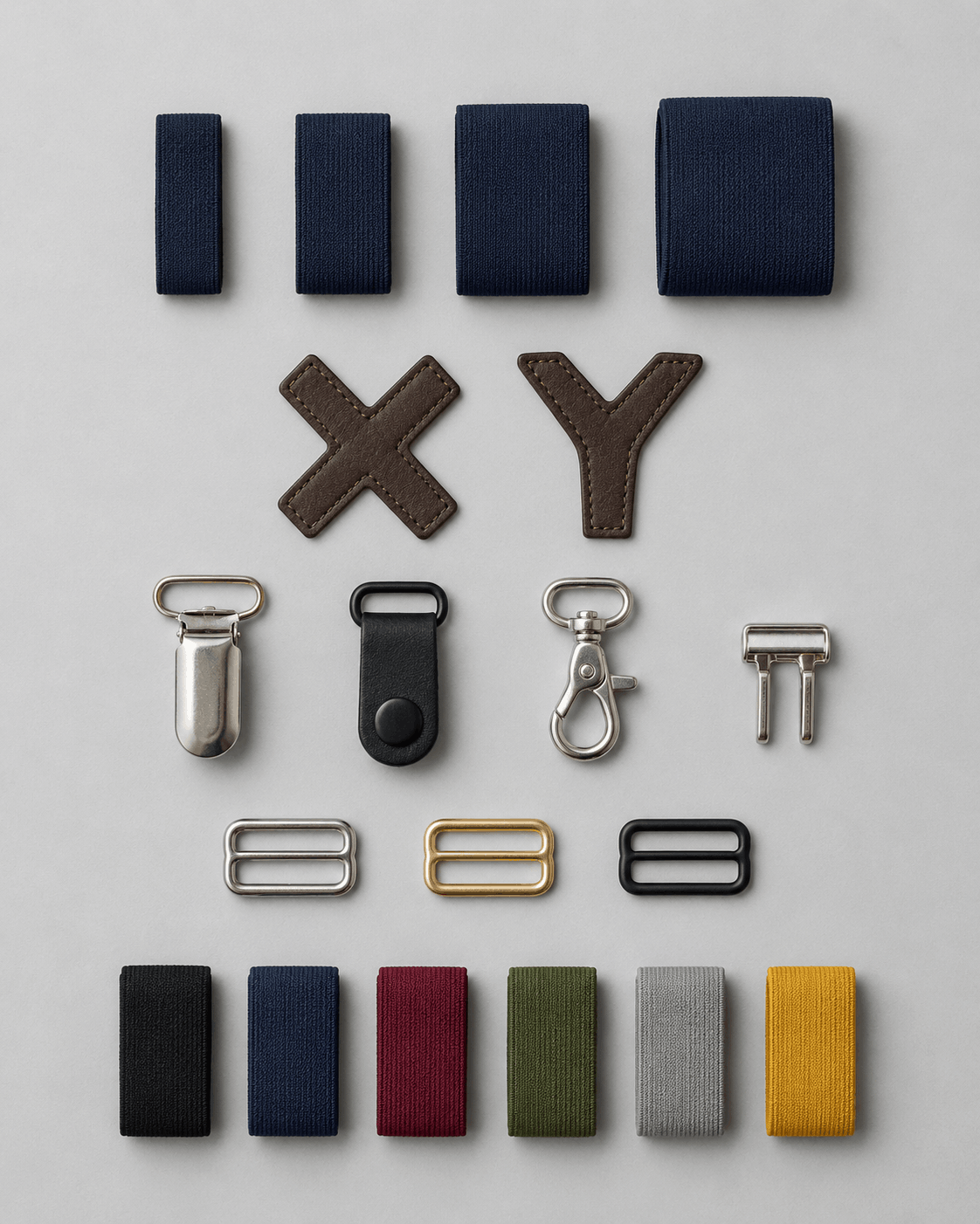 Suspender straps, leather ends, clips, and hardware laid out for building a custom pair of suspenders