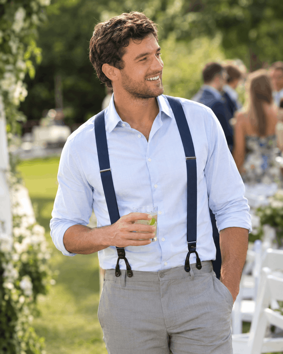 Wedding guest wearing navy Y-back suspenders and a light blue shirt at an outdoor summer wedding