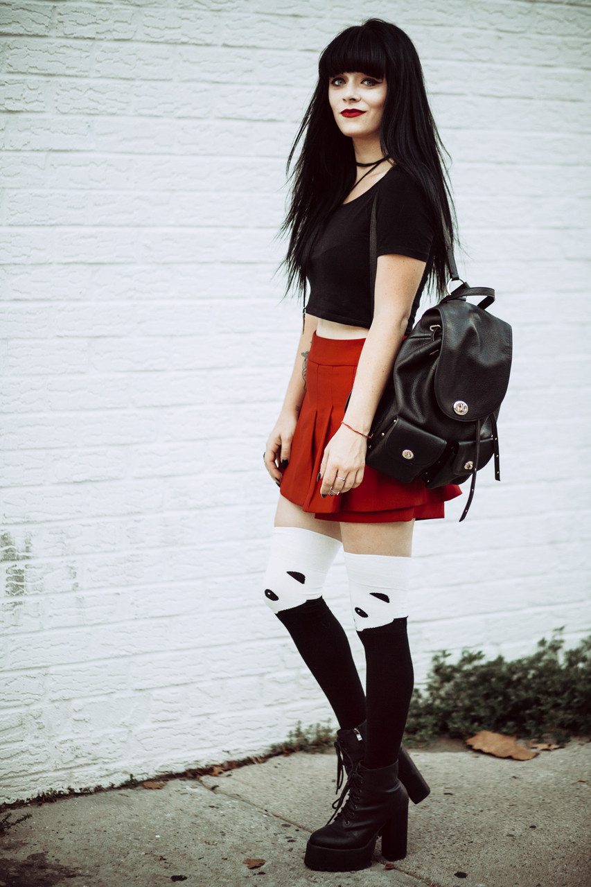 fashionable thigh highs with platform boots. Wearing red skirt and black top with a backpack