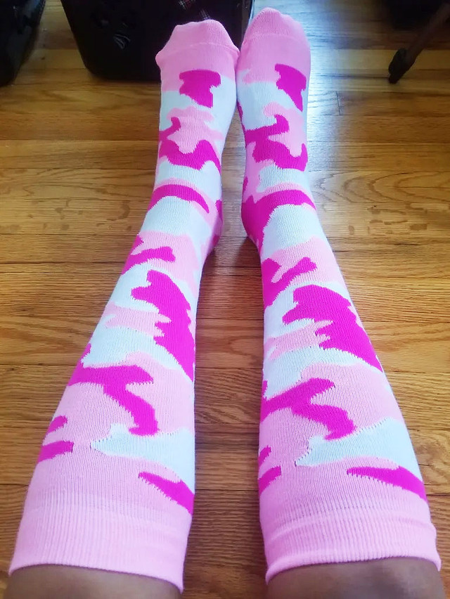 pair of pink camo socks stretched out on wood flooring