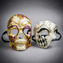 A pair of ornate masquerade masks featuring a purple and gold harlequin skull mask and a silver and black Venetian half mask with gold scrollwork and crackle finish, set against a gray background.