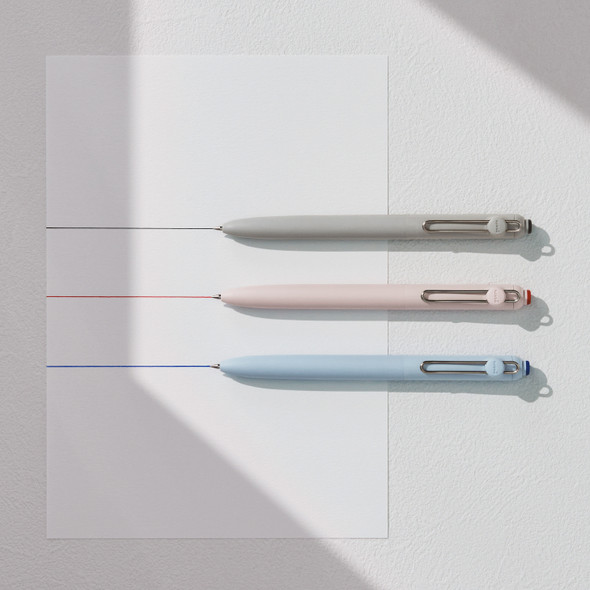 Uni-ball Zento pens in fog grey, adobe pink, and cloud blue barrels writing fine lines on white paper Uni-ball Zento pens in fog grey, adobe pink, and cloud blue barrels writing fine lines on white paper