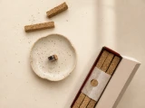 Espíritus del Ande by Cosmic Provisions hand pressed palo santo incense bars beside a ceramic incense dish with a small piece burning.