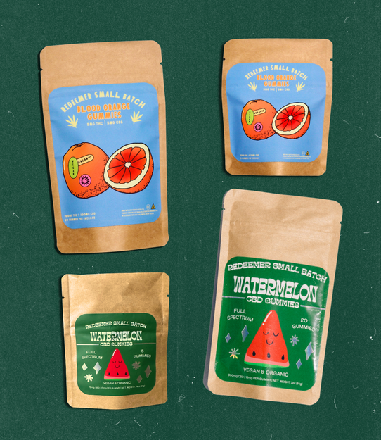 Four Redeemer gummy pouches. Blood Orange and Watermelon in both 5ct and 20ct — arranged on a green backdrop.