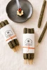 Cosmic Provisions hand rolled Palo Santo and Myrrh incense bundles with one incense stick burning in a ceramic holder.
