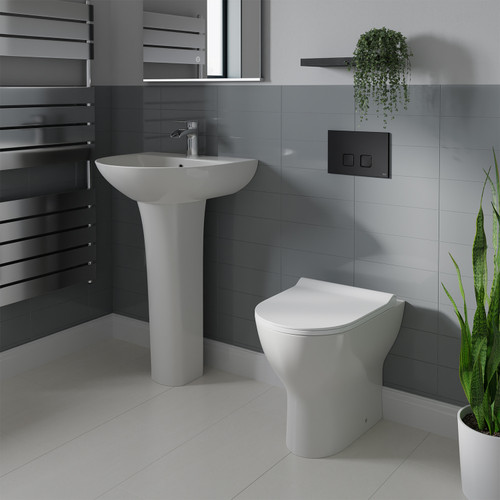 A modern basin and pedestal with back to wall toilet including concealed cistern and flush plate