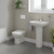 A modern basin and pedestal with back to wall toilet including concealed cistern and flush plate