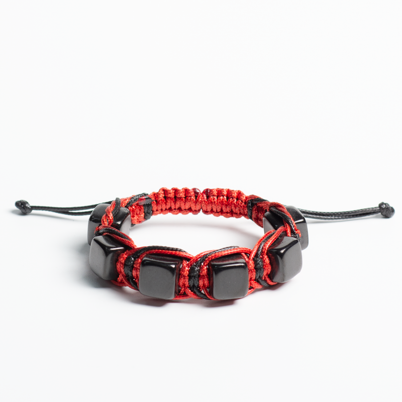 Black and red Arachne bracelet next to smoldering incense, representing passion and protection.