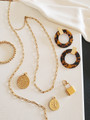 Elegant Gold Jewelry Displayed Laying Down. One Gold Bead Ball Bracelet. Two Gold Paperclip Chain Necklaces. Two Gold Greek Coin Medallion Necklace Pendants. Gold Statement Stainless Steel Padlock Necklace Pendant. Pair of Gold Brown and Black Tortoise Resin Earrings. | Mojo Supply Co