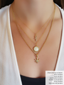 Woman Wearing White Shirt and Three Gold Necklaces. Top Necklace is Dainty Gold Necklace Chain with Rounded Dainty CZ Stone Cross Pendant, Middle Necklace is Beaded Gold Chain with Round White Shell and Gold Ball Detail Pendant, Bottom Necklace is Emily Gold Link Chain with Mary Jane CZ Pave Leaf | Mojo Supply Co