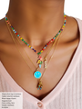 A Woman Wearing A Colorful Beaded Necklace Layered with Happy Charm, And Two Gold Filled Necklaces Layered With A Love Charm And A Blue Smiley Face Pendant | Mojo Supply Co