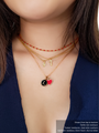Woman Wearing A Gold Beaded Necklace And Three  Filled Necklaces Layered With A Black Letter Pendant, A Red Heart Pendant, And Two Gold Number Necklace Charms 7 And 9 | Mojo Supply Co