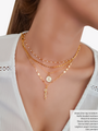 Woman Wearing A Gold Choker Necklace Layered With White Pearls And Three Gold Filled Necklaces Layered With Letter Pendant And A Gold Leaf Crystal CZ Studded Necklace Pendant | Mojo Supply Co