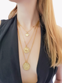 Woman With Long Hair Wearing Layered Gold Necklaces Including Ancient Horse Coin Pendant, Double Sided Greek Pendant And Large Gold Statement Ancient Coin Charm