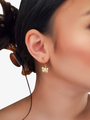 Woman Wearing A Gold Hoop Earring With A Gold Butterfly Charm