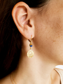 Woman Wearing Earrings Made With Gold Hoops Blue Connector Charm And Sun Coin Charms