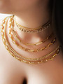 Woman Layered In Statement Necklaces In Paperclip Herringbone And Cuban Chain Styles