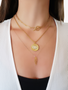 Woman Wearing Gold Layered Necklaces With An Evil Eye Pendant And Geometric Triangle Design | Mojo Supply Co