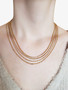 Woman Wearing Dainty Gold Adjustable Layering Necklace Collection Featuring Box Link And Snake Chain Designs