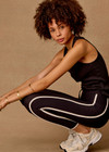 THE UPSIDE women's black Sol 25inch Midi Legging offers a soft and supportive fit with a mid rise waist, side stripe detailing, pockets and adjustable drawcord. Made for yoga and pilates.