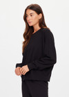 THE UPSIDE women's black organic cotton Lennox Raglan Crew Sweater offers a relaxed fit and features a classic crew neckline, ribbed. cuffs and hem. Finished with a subtle embroidered arrow logo at back. The perfect everyday sweater, made to last.