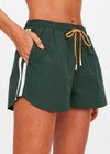 THE UPSIDE women’s green Billie Run Short is a mid-rise style featuring cream mesh binding down the sides and an orange drawcord. Made for high impact.