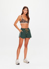 THE UPSIDE women’s green Billie Run Short is a mid-rise style featuring cream mesh binding down the sides and an orange drawcord. Made for high impact.