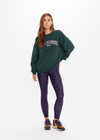 THE UPSIDE women's dark green Alumni Coolum Crew Neck Sweater is made from organic cotton and feature small side splits, front zip pocket and side pockets.