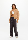 THE UPSIDE women's tan Carlotta Bomber Jacket is made from recycled fabric and made for a cropped fit. This fully insulated jacket features side seam pockets and metal arrow logo zipper.