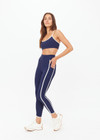 THE UPSIDE women’s navy recycled peached Samara 25inch Legging is a soft & supportive fit and features side pockets and contrast cream stripes with curved hem detail. Made for pilates.