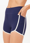 THE UPSIDE women’s navy recycled peached Samara 3.5inch Spin Short offers a soft & supportive fit and features side pockets and contrast cream stripes . Made for pilates.