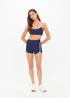 THE UPSIDE women’s navy recycled peached Samara 3.5inch Spin Short offers a soft & supportive fit and features side pockets and contrast cream stripes . Made for pilates.