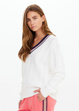 THE UPSIDE women’s cream organic cotton Espada Louie V Neck Sweater is a regular, chunky cable knit design with a navy and rose striped neckline. Made for everyday.