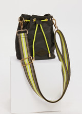 THE UPSIDE women's olive green Oxford Bucket Bag features a striped woven strap and neon paracord with gold metal detailing. Made for lifestyle.
