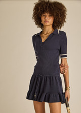 THE UPSIDE women's navy tennis Plume Knit Collared Dress fits true-to-size and features a drop waist with gathered skirt and a drawcord with tennis charms.