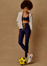THE UPSIDE women’s navy recycled Eco Tech Salvador 25inch Midi Legging is mid rise and features side seam pockets, a cuffed hem and drawcord waist. Made for yoga and pilates.