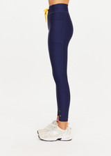 THE UPSIDE women’s navy recycled Eco Tech Salvador 25inch Midi Legging is mid rise and features side seam pockets, a cuffed hem and drawcord waist. Made for yoga and pilates.