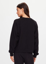 THE UPSIDE women's black organic cotton Lennox Raglan Crew Sweater offers a relaxed fit and features a classic crew neckline, ribbed. cuffs and hem. Finished with a subtle embroidered arrow logo at back. The perfect everyday sweater, made to last.