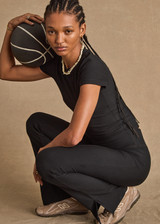 THE UPSIDE women's black Divina Isabella Baby Tee is designed for a soft and supportive fit in cotton modal fabrication and features a printed logo arrow in cream. Made for lifestyle.