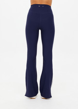 THE UPSIDE women's navy recycled peached Florence Flare Pant is a high-rise pant in a breathable fabric, featuring cream side stripes. Perfect for pilates.